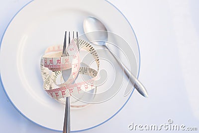 fork is wrapped in yellow measuring tape on dish with spoon. Nutrition concept Stock Photo
