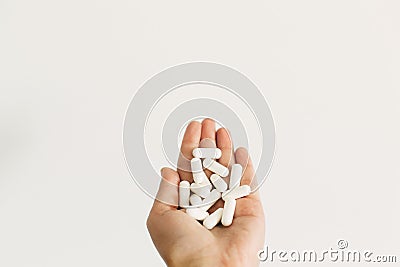 Dietary supplements. Health support and treatment. Hand holding magnesium capsules on white wall background. White pill. Stock Photo