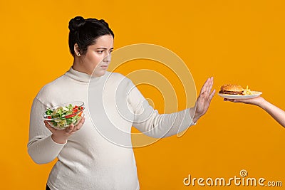 Overweight girl refusing fast food, holding bowl with fresh vegetable salad Stock Photo