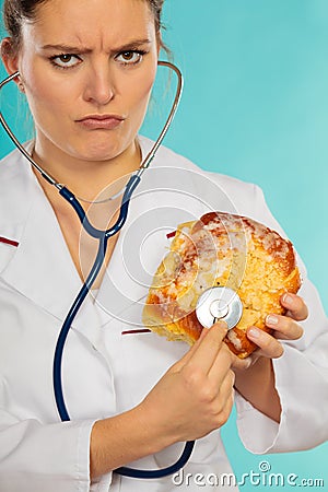 Dietitian examine sweet roll bun with stethoscope. Stock Photo