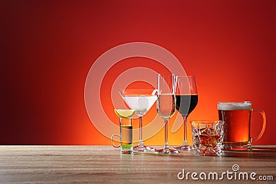 Different alcohol drinks on wooden table against red background. Space for text Stock Photo