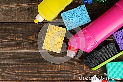 Different bottles with cleaning products and detergents and washcloths in a blue bucket on a brown wooden table. top view Stock Photo