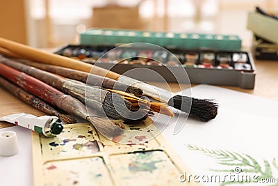 Different brushes, colorful paints, palette and drawing on table indoors, closeup. Artist`s workplace Stock Photo