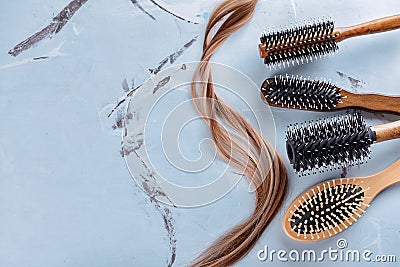 Different brushes and strand of hair on color background Stock Photo