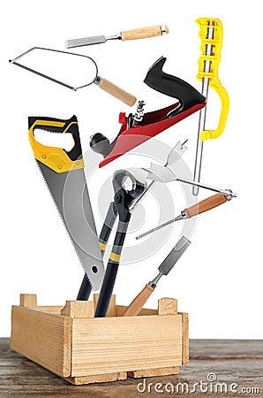 Different carpenter`s tools falling into wooden box on white background Stock Photo