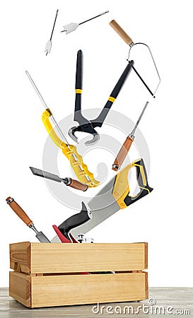 Different carpenter`s tools falling into wooden box on white background Stock Photo