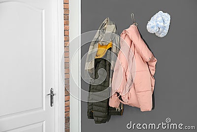Different clothes hanging on grey wall near door Stock Photo