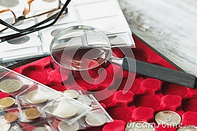 Different collector`s coins with a magnifying glass and glasses Stock Photo