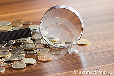 Different collector`s coins with a magnifying glass, soft focus background Stock Photo