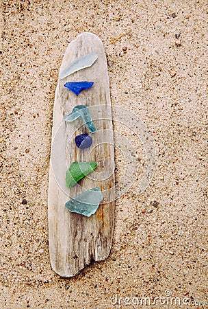 Blue, green, white sea glass or beach glass on driftwood in beach. Stock Photo