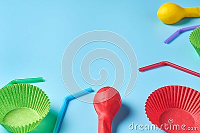 Different color paper molds for baking muffins, balloon and straw scattered on blue desk on kitchen Stock Photo