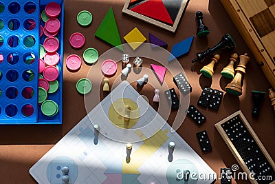 Different desktop games, figures, dices, parts on the brown table. Home entertaiment, indoor games. Stock Photo