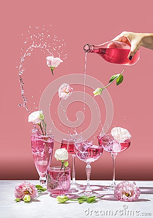 Different elegant champagne glasses with sparkling wine, women hand is pouring rose wine from bottle to coupe glass Stock Photo