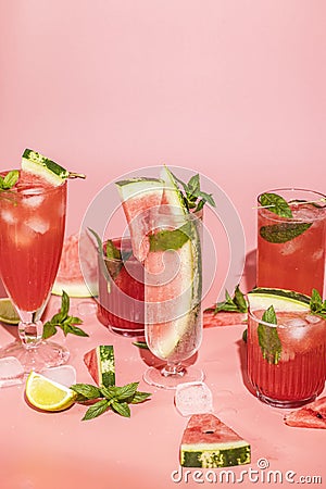 Different elegant glasses with watermelon cocktail. Splash, splatter, water drops on the pink background with sun light Stock Photo