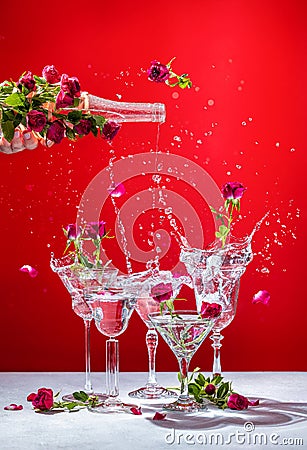 Different elegant martini glasses with sparkling wine, women hand is pouring rose wine from bottle to glass Stock Photo
