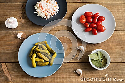 Different fermenting foods in plates. Homemade sauerkraut with marinated cucumbers and tomatoes on wooden background Stock Photo