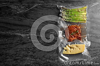 Different food products in vacuum packs on black marble table, flat lay. Space for text Stock Photo