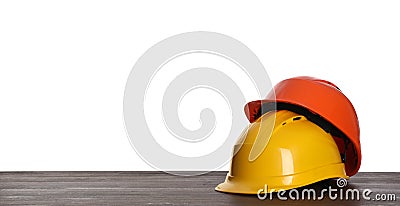 Different hard hats on wooden table against white background. Space for text Stock Photo
