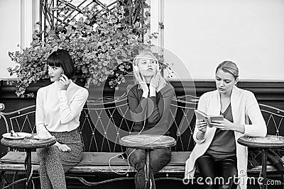 Different interests. Group pretty women cafe terrace entertain themselves with reading speaking and listening Stock Photo