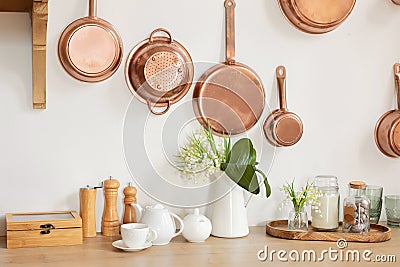 Different kind of cookware and ceramic plates on tabletop wooden kitchen. Set of copper saucepans, pans, pots and ladle hanging in Stock Photo