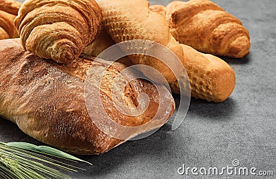 Different kinds of bread rolls on gray board, closeup. Kitchen or poster design for a local bakery. Baguette, croissant and Stock Photo