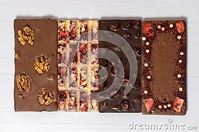 Different kinds fof chocolate bars laying down in a row on wooden white background. Stock Photo