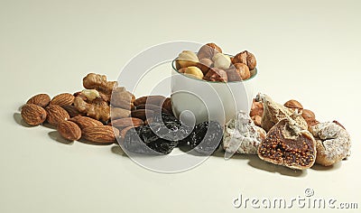 Different kinds of nuts in white cup, hazelnuts, almonds, walnut and dried fruits figs, plums. Vegetarian food Stock Photo