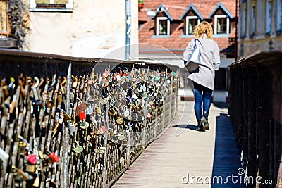 Different love locks attached to the metal grid of a bridge in E Editorial Stock Photo