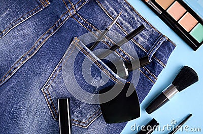 Different makeup products composition with jeans on blue background Stock Photo