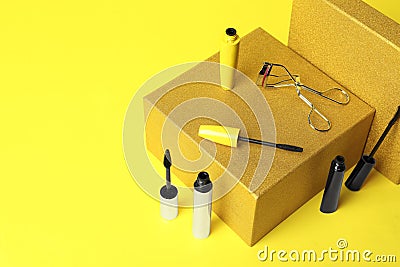 Different mascaras and eyelash curler on yellow background. Makeup product Stock Photo