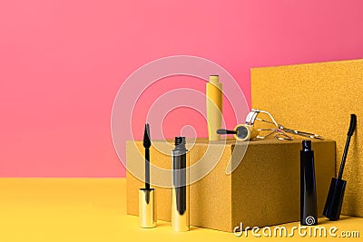 Different mascaras and eyelash curler on yellow, space for text. Makeup product Stock Photo