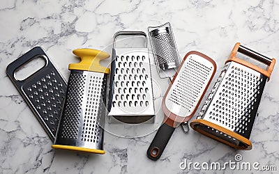 Different modern graters on white marble table, flat lay Stock Photo