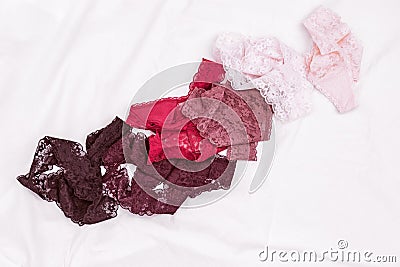 Different panties fow women. Fashion trendy lace lingerie. Colorful underwear scattered on bed sheet Stock Photo