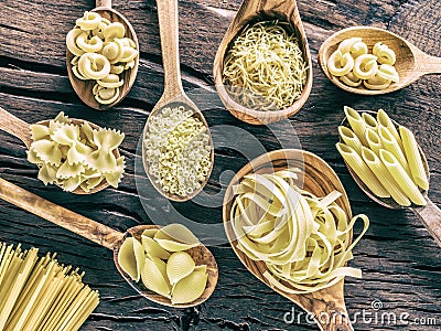Different pasta types in wooden spoons on the table. Top view. Stock Photo