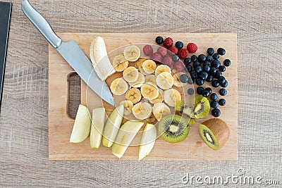 Different pieces of fresh fruits on a wooden board for cutting. Healthy food concept Stock Photo