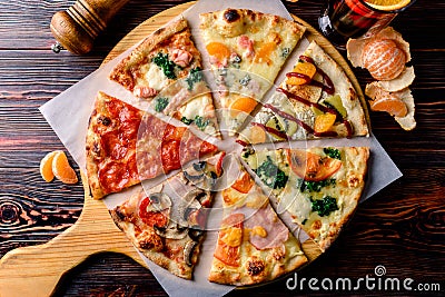 Different pizza slices on a wooden table mix Stock Photo