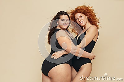 Different Size. Diversity Women Portrait. Hugging Female Friends Posing On Beige Background. Stock Photo