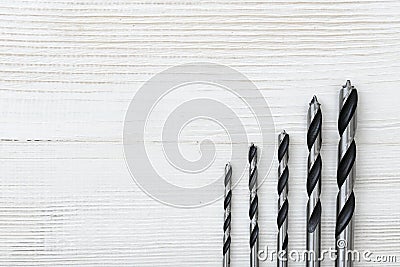 Different size drills posted from the highest to lowest on a wooden surface. Stock Photo