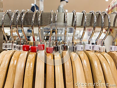 Different sized hanger with dress size tags XL, L, M, S t-shirts displayed in shop for sale Stock Photo