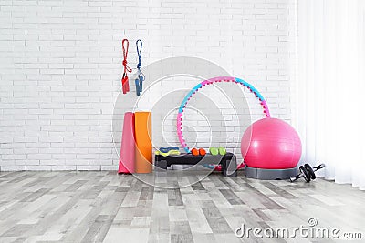 Different sports equipment near white brick wall in gym Stock Photo
