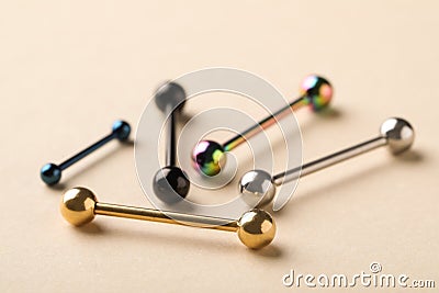 Different stylish barbells on beige background, closeup. Piercing jewelry Stock Photo