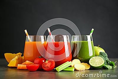 Different tasty juices and fresh ingredients on grey table against black background Stock Photo