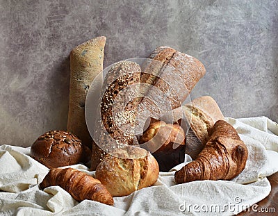 Different types of baking still life. Buns croissants, muffins and loaves, bread patties on textile drapery. Rustic Stock Photo