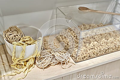 Different uncooked macaroni on wooden stand indoors Stock Photo