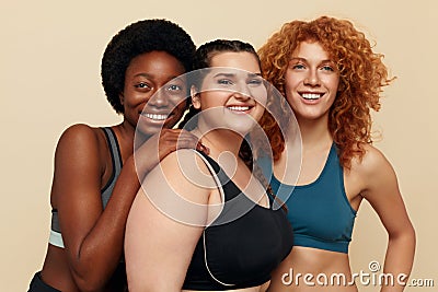 Different Women. Group Of Diversity Models Portrait. Smiling International Female In Fitness Clothes Posing On Beige Background. Stock Photo