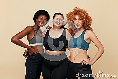 Different Women. Group Of Diversity Models Portrait. Smiling Multicultural Female In Fitness Clothes Posing On Beige Background. Stock Photo