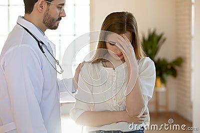 Attentive compassionate young male doctor supporting frustrated crying female patient Stock Photo