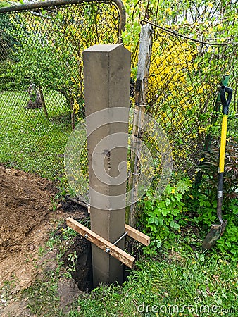 Dig a deep hole in the soil to pour mortar on the fence posts to strengthen the foundation Stock Photo