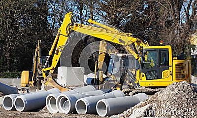 Digger, mini excavator and dozer in a road construction site. Pipes concrete precast in front Stock Photo