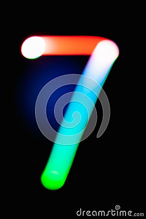 Digit 7. Seven. Glowing numbers on dark background. Abstract light painting at night. Creative artistic colorful bokeh. New Year. Stock Photo